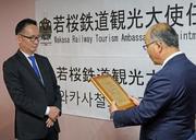 　若桜鉄道の矢部雅彦専務（右）から観光大使の任命状を受け取る尹熙一さん＝１１月、韓国・大田（共同）