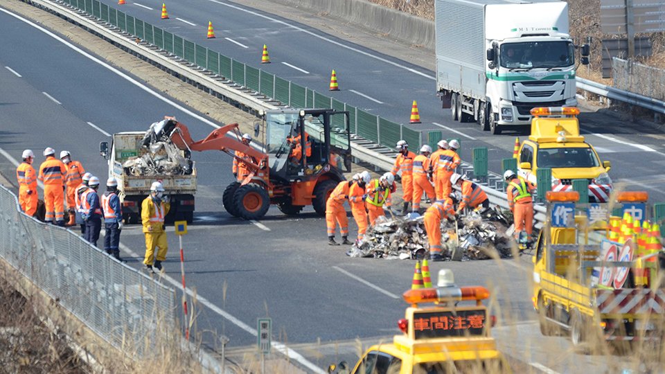 中央自動車道下り線の道路上に散乱した鉄くずなどを撤去する作業員＝２日午前１０時５８分、中津川市千旦林