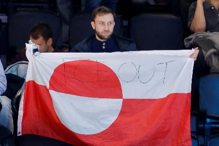 　アイスホッケー男子の米国―デンマーク戦の会場で、グリーンランドの旗を掲げる観客。「ＩＣＥ　ＯＵＴ」と書かれていた＝１４日、イタリア・ミラノ（共同）