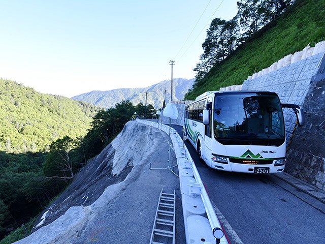 片側交互通行となった箇所を通るバス＝２２日午前７時１分、高山市丹生川町久手