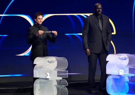 　サッカーＷ杯北中米３カ国大会の組み合わせ抽選で、第１ポットのくじを引くトム・ブレイディさん。右はシャキール・オニールさん＝５日、米ワシントン（共同）