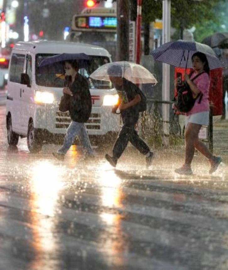 　大雨の中、傘を差して歩く人たち。前線などの影響で関東甲信と東北地方で大気の状態が非常に不安定になった＝１０日夕、東京・池袋