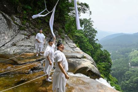 　「那智の滝」の上に架かるしめ縄を張り替える熊野那智大社の神職＝９日午前、和歌山県那智勝浦町