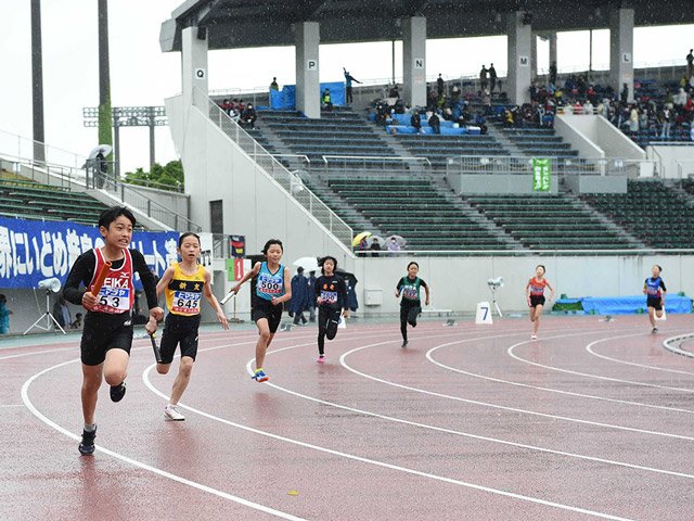 雨の中、バトンを手に懸命に走る小学生＝２９日午前９時２１分、岐阜市長良福光、長良川競技場