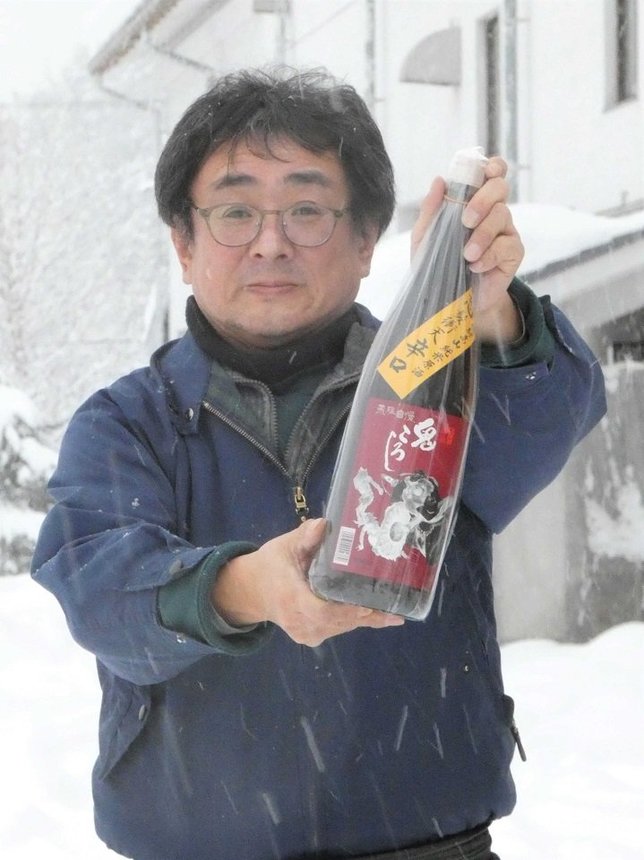 最辛の「鬼ころし」を手に、銘柄の由来を教えてくれた蔵元・老田英夫さん＝岐阜県高山市清見町牧ケ洞、老田酒造店