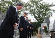 　相嶋静夫さんの墓前で謝罪する（左から）最高検の小池隆公安部長、東京地検の市川宏次席検事、警視庁の鎌田徹郎副総監。奥２人は相嶋さんの息子＝２５日午前、横浜市の霊園（代表撮影、画像の一部を加工しています）