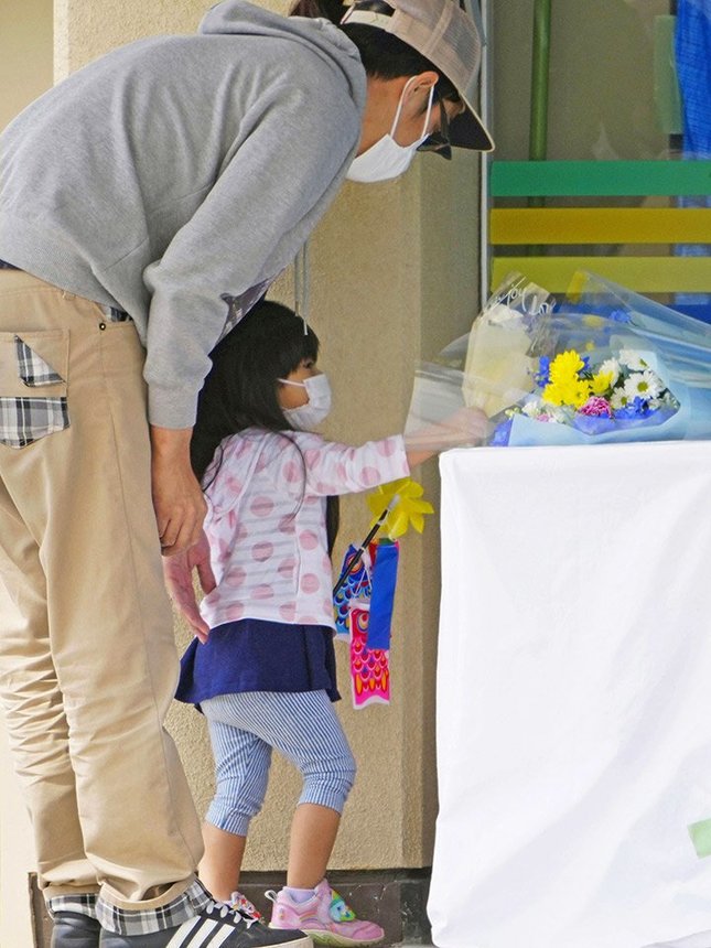 観光船事故犠牲者の遺体が安置された施設前の献花台に、花を手向ける親子＝２９日、北海道斜里町