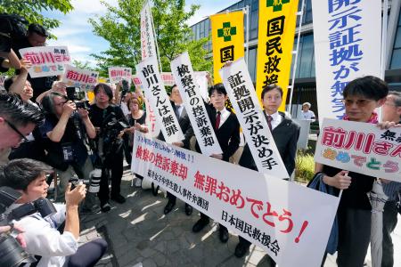 　福井中３殺害事件の再審判決を受け、「前川さんは無罪」などと書かれた紙を掲げる弁護士ら＝１８日午後、名古屋高裁金沢支部前