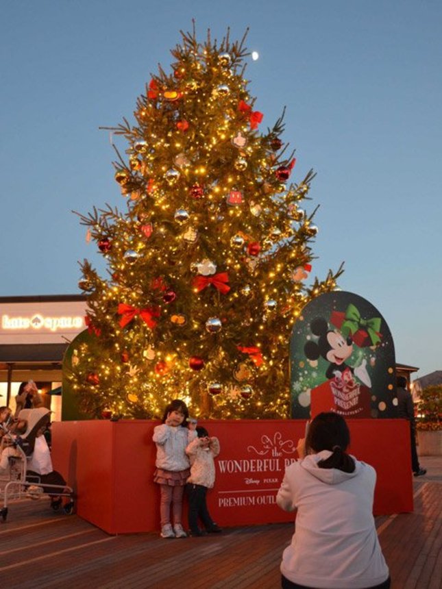 ディズニーキャラクターが飾られたクリスマスツリーを背景に記念撮影する子どもたち＝土岐市土岐ケ丘、土岐プレミアム・アウトレット