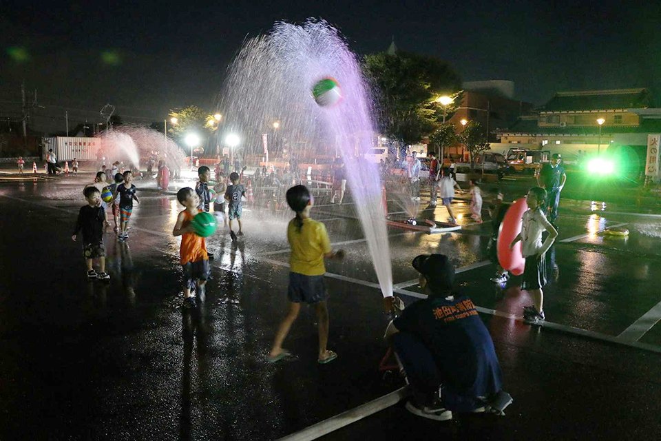 水を浴びながら、ビーチボールを楽しむ子どもたち＝池田町六之井、町中央公民館南駐車場