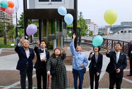 　尼崎ＪＲ脱線事故から２０年、ＪＲ伊丹駅前で安全を祈願し風船を飛ばす人たち。左から３人目は脱線事故で重傷を負った増田和代さん＝２５日午前