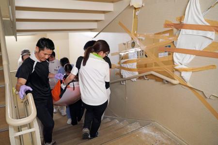 　階段を使って患者を運ぶ熊本総合病院のスタッフ＝７月３１日、熊本県八代市