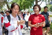 　中国の全国一斉大学入試「高考」の初日を終えた受験生（左）と言葉を交わすチャイナ服姿の保護者＝７日、北京（共同）