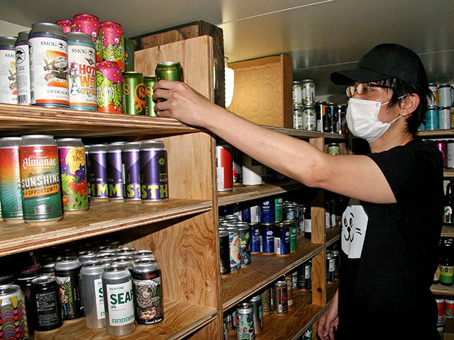 在庫管理をする阪本真記さん。国内外のエールビール約２９０種類を扱う＝岐阜市岩崎