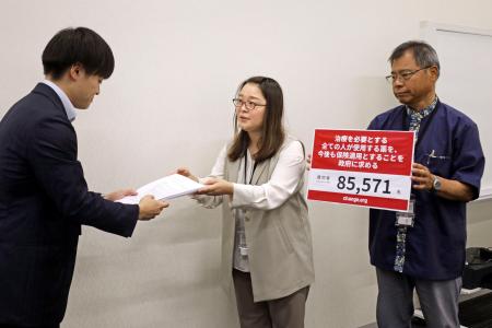 　厚労省の担当者に署名を提出する大藤朋子さん（中央）＝１８日午前、参院議員会館
