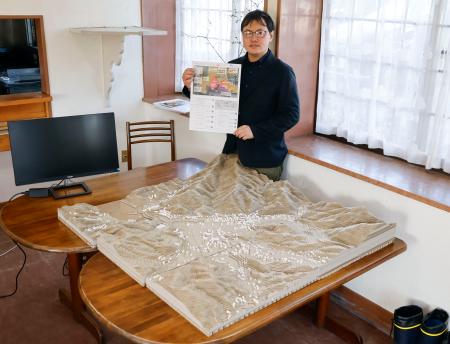 　大規模山林火災の伝承施設で展示が予定されている綾里地区の立体地形図と阿部正幸さん＝１９日、岩手県大船渡市