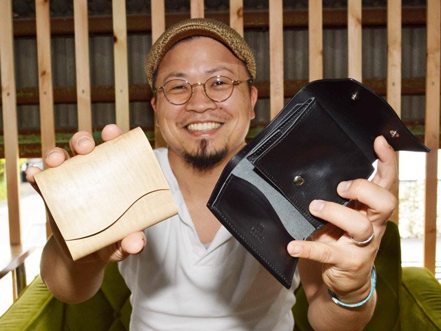 木と革を合わせた三つ折り財布「Ｐａｇｎｕｓ」を手にする吉田翔太社長＝大垣市築捨町、Ｌｅａｗｏｏｄ
