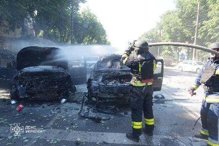 　３日、ロシア軍による攻撃で被弾した車両の消火に当たる消防隊員ら＝ウクライナ北東部スムイ州（ロイター＝共同）