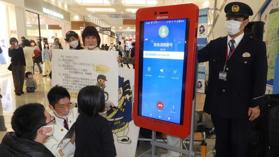 警察官から助言を受け１１０番通報を体験する参加者＝各務原市那加萱場町、イオン各務原店