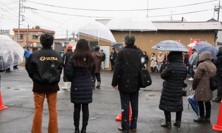 　雪が降る中、候補者の街頭演説に耳を傾ける人たち＝７日午後、茨城県行方市