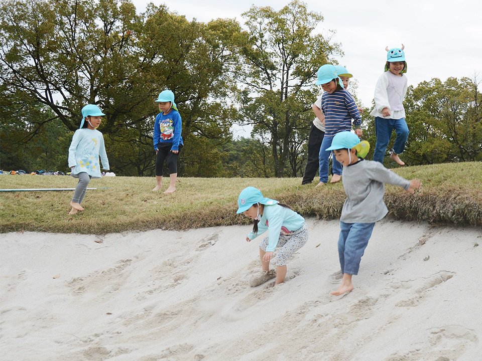 はだしでバンカーに飛び込み、遊ぶ園児＝関市山田芳洞、岐阜関カントリー倶楽部