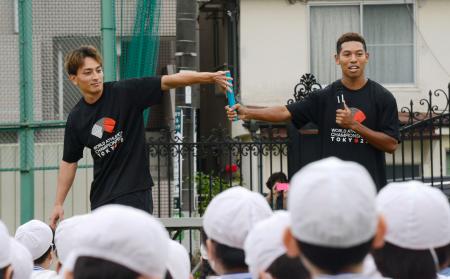 　東京都内の小学校を訪れ、児童にバトンパスを説明する陸上男子のサニブラウン・ハキーム（右）と橋岡優輝＝１９日