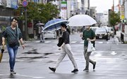 台風７号接近で風雨が強まる中、交差点を歩く人たち＝１５日午前８時１０分、岐阜市神田町