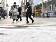 雪が舞う中を歩く人たち＝２５日午前８時５分、岐阜市神田町