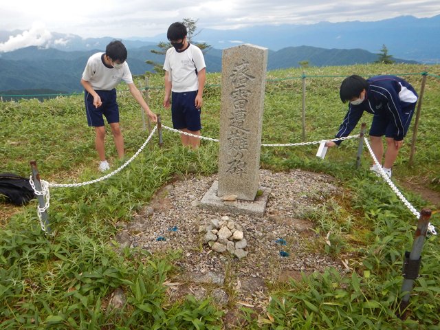 「落雷遭難の碑」の周囲にササユリの種をまく生徒＝長野県阿智村