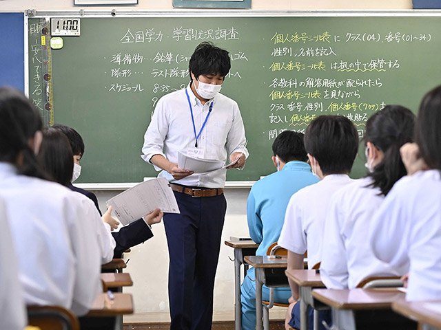 全国学力・学習状況調査で、解答用紙を配布する教員＝２７日午前８時２６分、岐阜市下土居、青山中学校