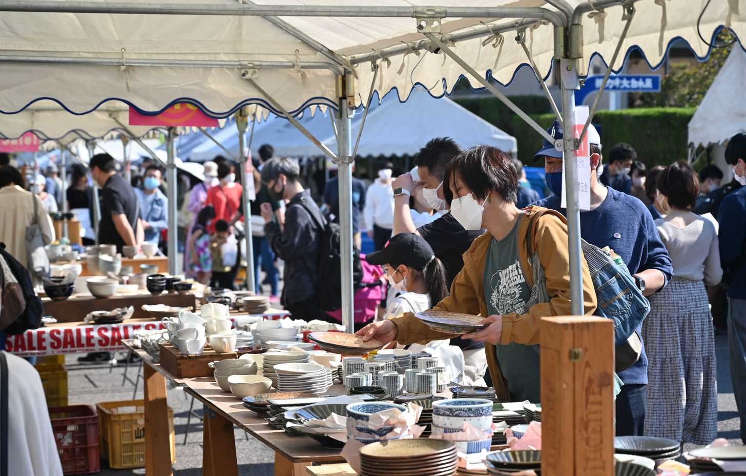 ずらりと並んだ陶磁器を品定めする来場者＝土岐市泉北山町、織部ヒルズ