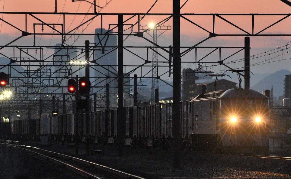 朝焼けに浮かび上がる岐阜の町を背景に、通過していく貨物列車。早朝の静寂の中、走行音が遠くまで響き渡る＝岐阜市今嶺