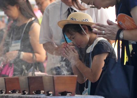 　終戦の日を迎え、千鳥ケ淵戦没者墓苑で手を合わせる子ども＝１５日午前９時２４分、東京都千代田区