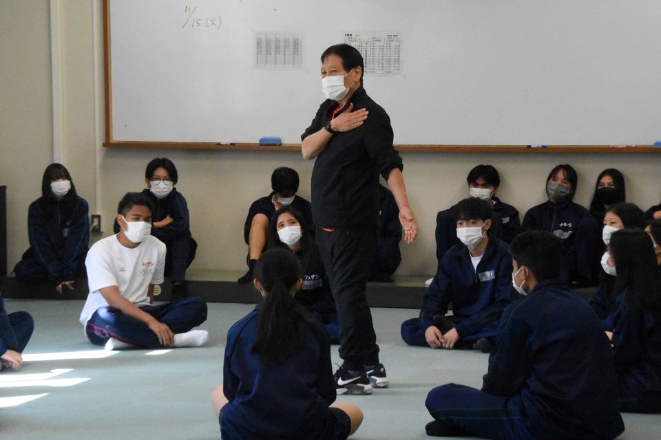 生徒たちにゲームを説明する西川信廣さん（中央）＝可児郡御嵩町御嵩、東濃高校