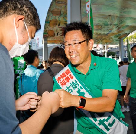 　街頭演説に集まった人とタッチを交わす古謝玄太氏＝１２日午後、那覇市