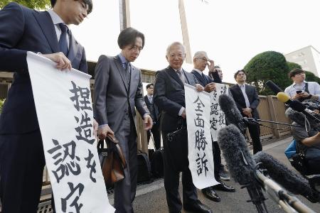 　大川原化工機訴訟の東京高裁判決を受け、「全面勝訴」と書かれた紙を手にする大川原正明社長ら＝５月、東京高裁前