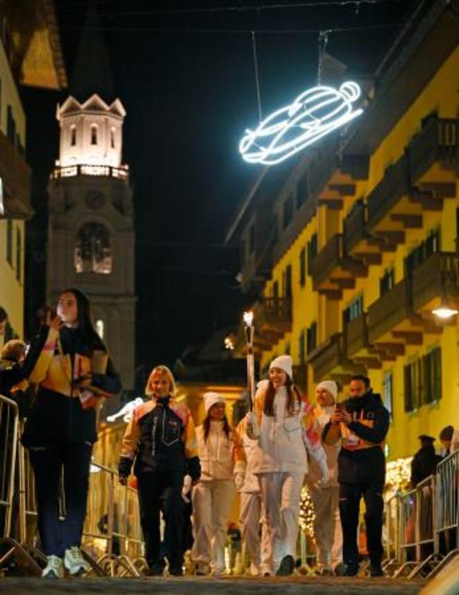 　イタリア・コルティナダンペッツォのメインストリートを、聖火を掲げて進むランナー＝３日（共同）