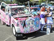 痛車と記念撮影をするコスプレをした来場者＝同