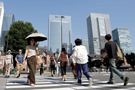 　暑さの中、ＪＲ東京駅前を行き交う人たち＝１７日午後