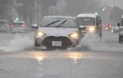 一部が冠水した道路を走る車（一部画像加工）＝８日午後３時２８分、岐阜市神田町（撮影・堀尚人）
