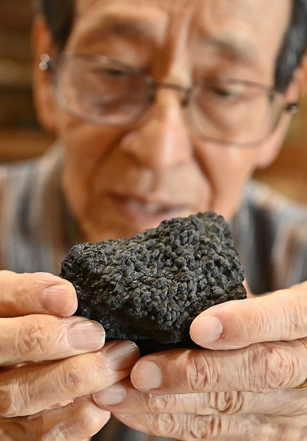 炭になった配給米を手にする篠田隆夫さん＝２日、岐阜市養老町