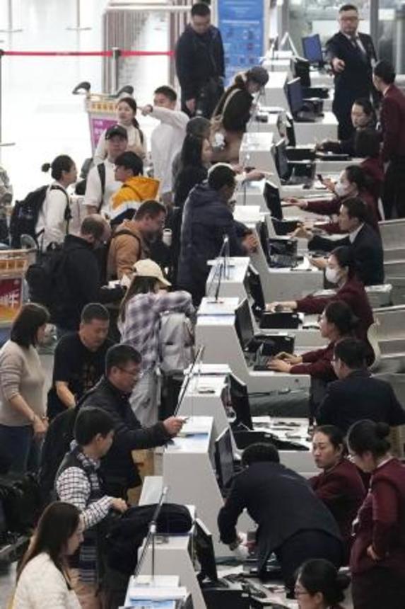 　昨年１１月、北京首都空港の日本便などを扱うカウンターで搭乗手続きをする人たち（共同）