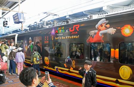 　特別ラッピング列車「スーパーマリオトレイン」の前で記念撮影する人たち＝２９日午前、ＪＲ博多駅