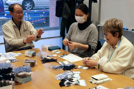 　しおりにリボンを通す「空色の会」のメンバーら＝４日、兵庫県川西市