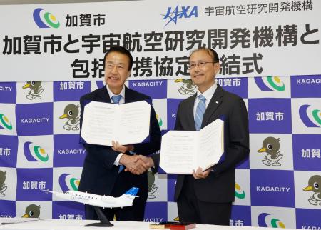 　空飛ぶ車の実用化に向け、協定書を交わす石川県加賀市の宮元陸市長（左）とＪＡＸＡ担当者＝２５日午後、加賀市役所