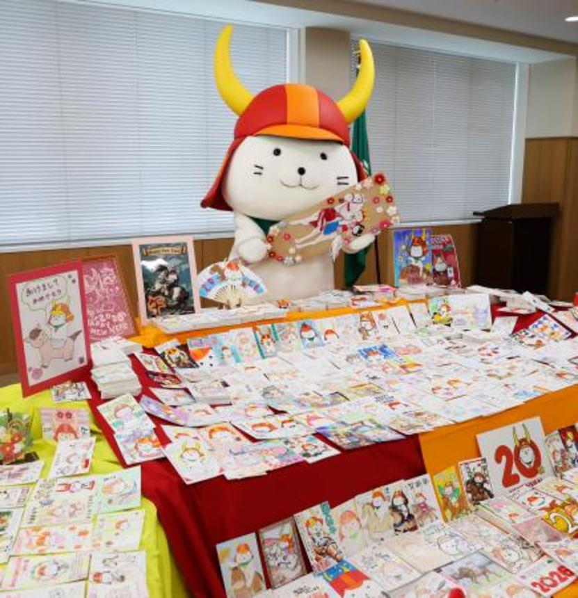 　届いた年賀状の山を前に羽子板を持って喜ぶ「ひこにゃん」＝７日午後、滋賀県彦根市役所