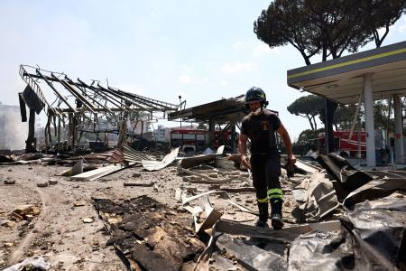 　４日、イタリア・ローマのガソリンスタンドで起きた爆発事故の現場で活動する消防隊員（ロイター＝共同）