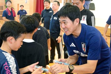 　小中学生らにボールペンを手渡すサッカー日本代表の森保監督＝１６日、熊本県氷川町
