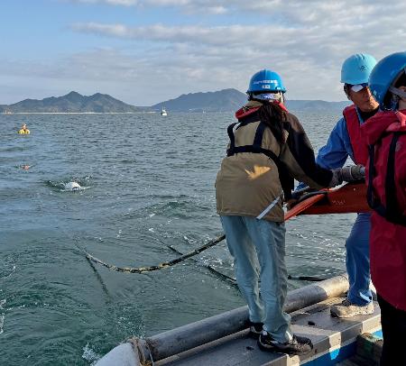 　愛媛県上島町の沖合で、海面に探査装置を延ばす産総研の研究員ら＝２０２５年１１月（産総研提供）