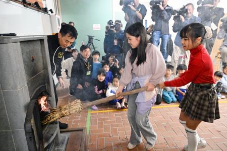 　まきストーブに火をともす神戸市立六甲山小の児童ら＝２３日午前